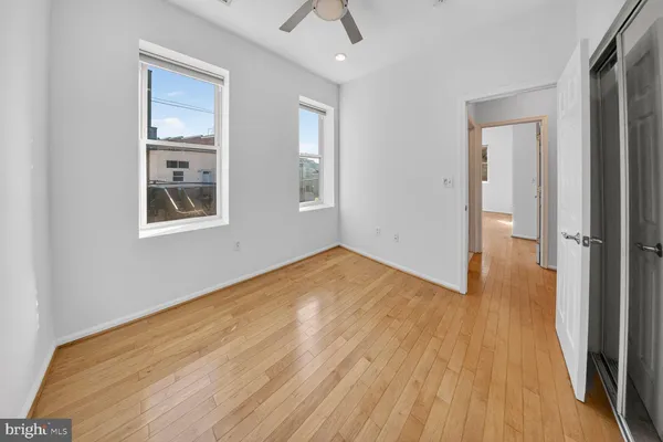 a view of empty room with wooden floor and fan