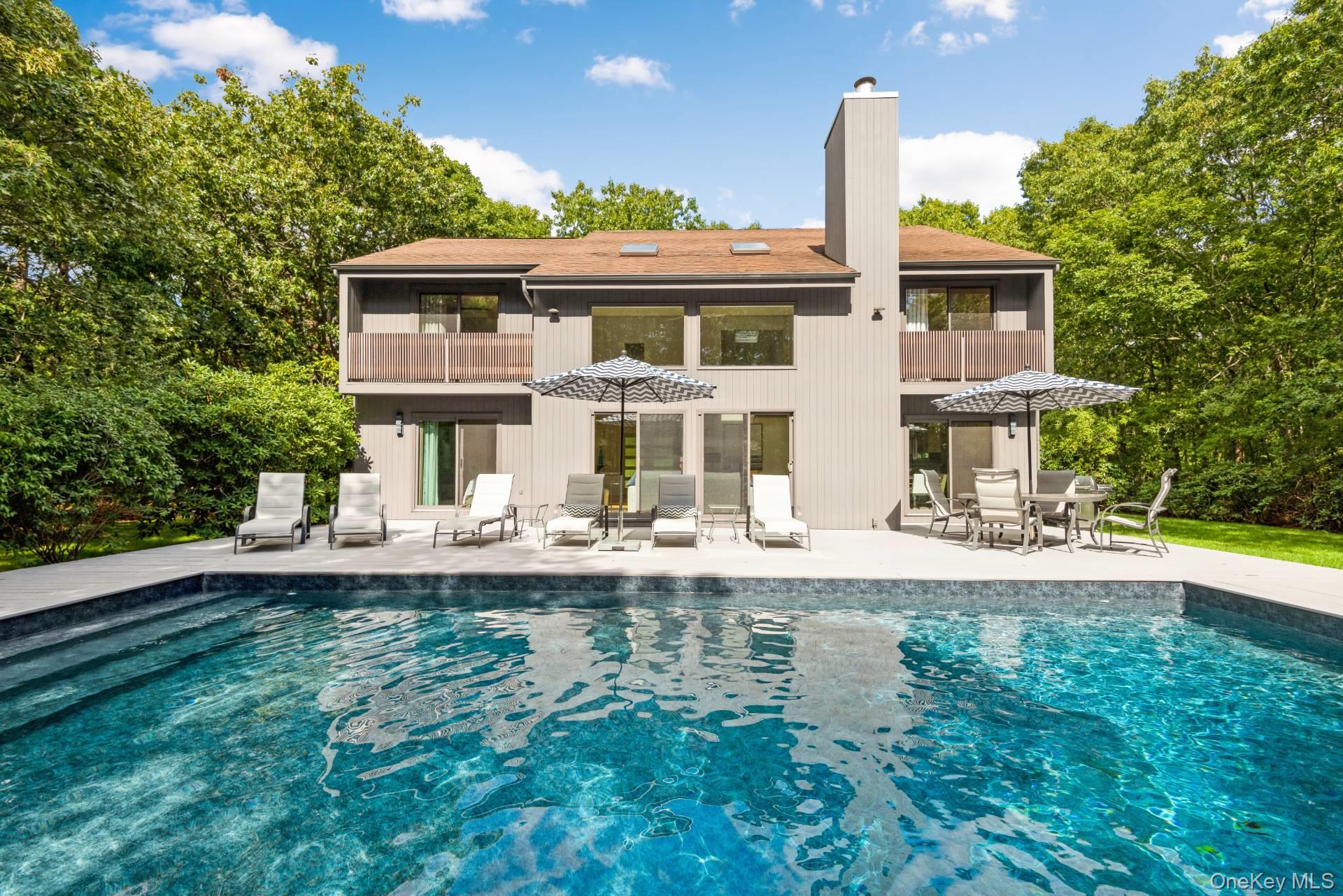 1 Deer Path Quogue, NY 11959 - Photo 34 of 38 a front view of a house with swimming pool having outdoor seating