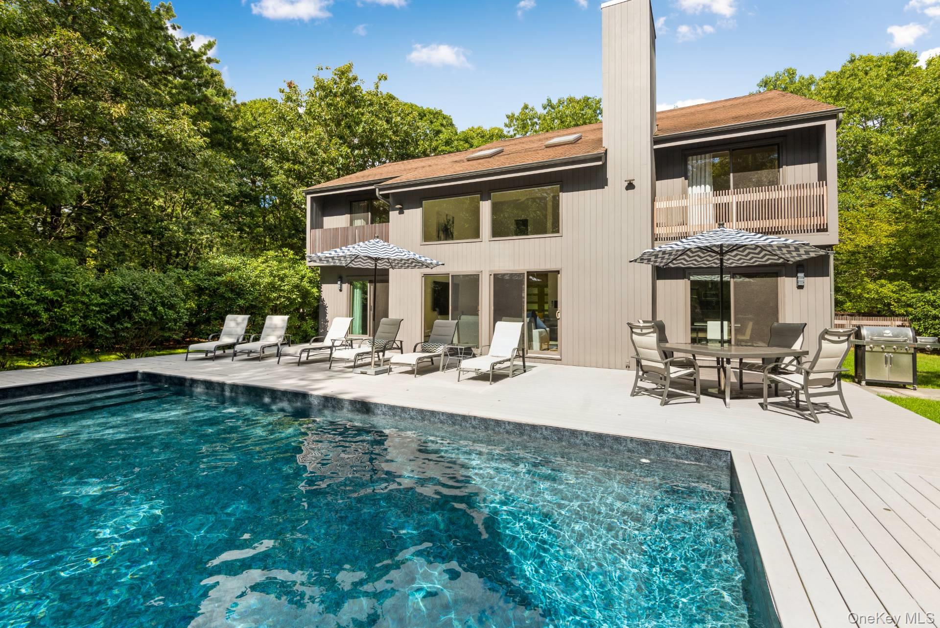 1 Deer Path Quogue, NY 11959 - Photo 36 of 38 Back of property with an outdoor pool, outdoor dining space, a patio area, and a wooden deck