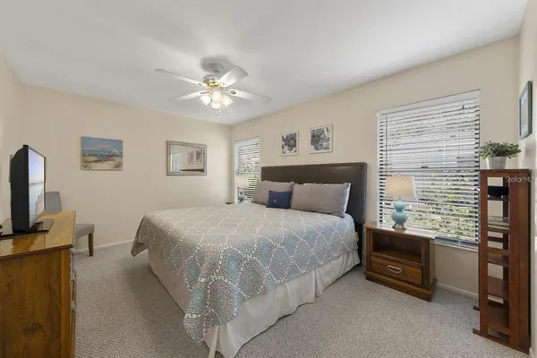 a bedroom with a bed a chandelier and a flat tv screen on a dresser