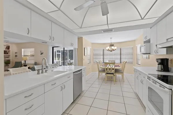 a large white kitchen with a large window appliances and cabinets