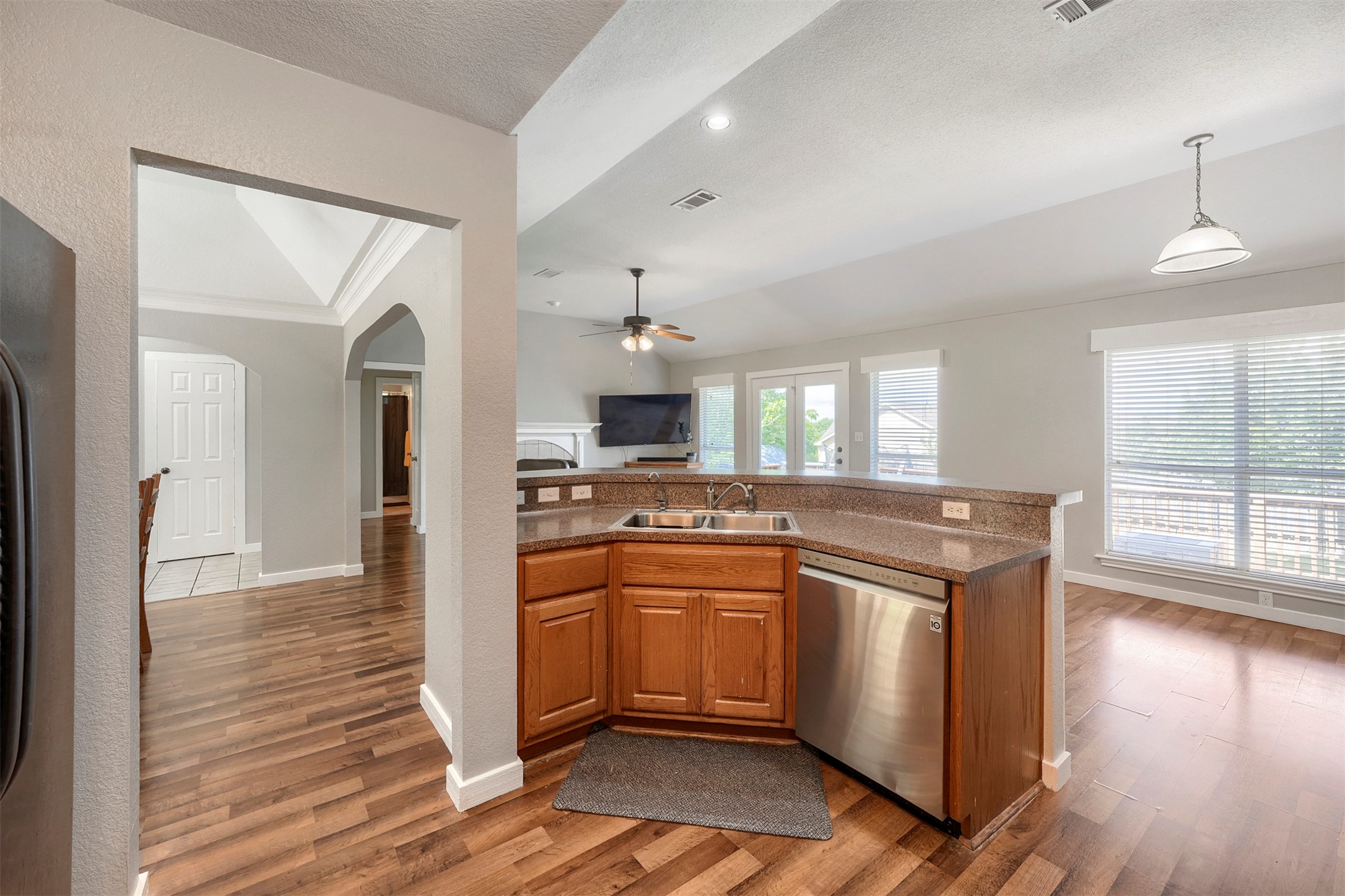 1105 2nd Street Jarrell, TX 76537 - Photo 9 of 27 A corner kitchen sink with stainless steel appliances connects to an open living area, featuring vaulted ceilings and abundant natural light.