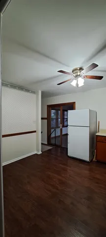 a view of an empty room with a window and a kitchen