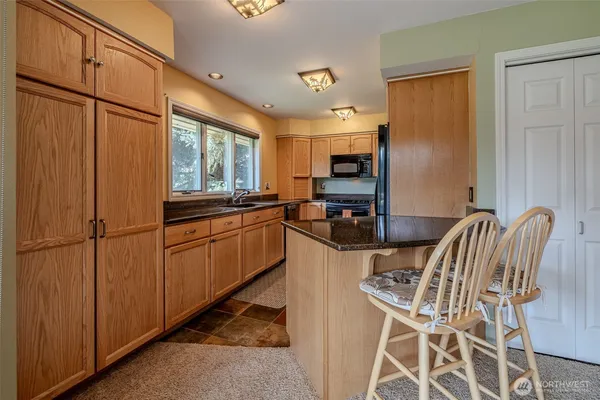 a kitchen with stainless steel appliances granite countertop a stove a sink a refrigerator with a dining table and chairs