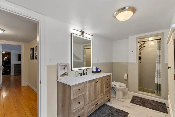 a bathroom with a double vanity sink toilet mirror and windows