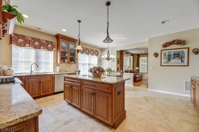 a kitchen with stainless steel appliances granite countertop a stove a sink dishwasher and a wooden cabinets