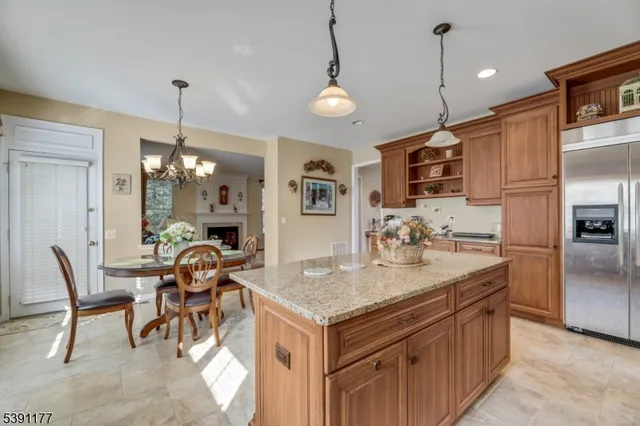 a kitchen with stainless steel appliances granite countertop a stove a refrigerator a oven a dining table and chairs with wooden floor