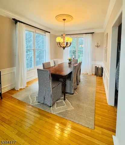 a dining room with wooden floor a chandelier a glass table and chairs