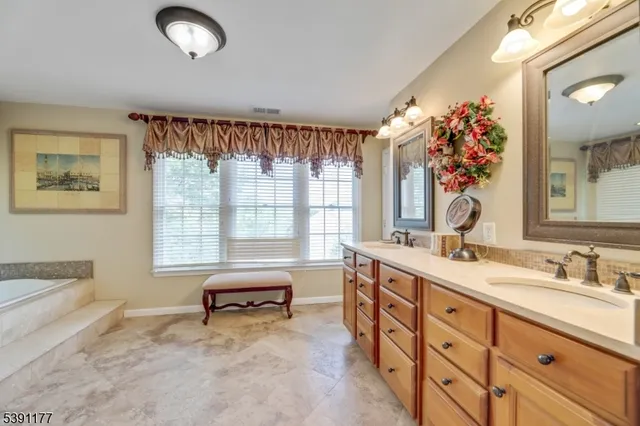 a spacious bathroom with a granite countertop sink mirror and a bathtub