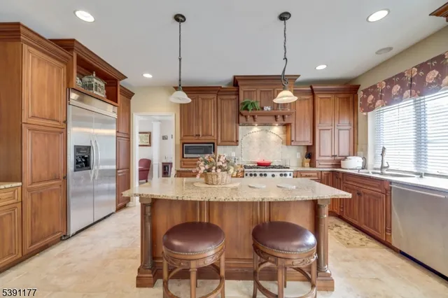 a kitchen with granite countertop a sink a center island and stainless steel appliances