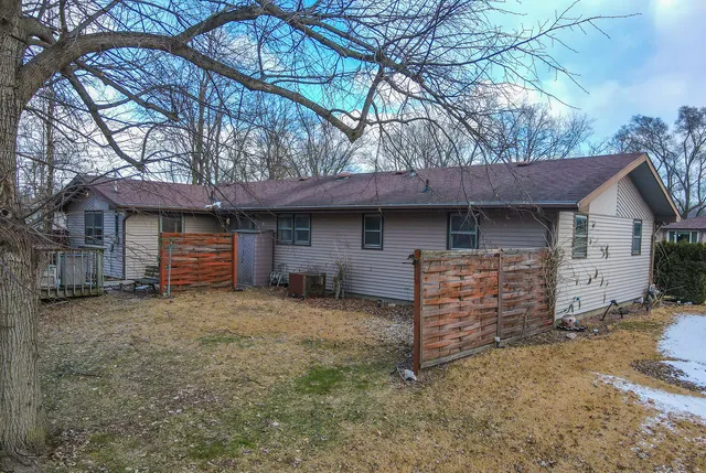 a view of house with a yard and wooden fence