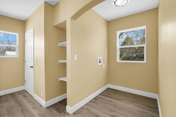 a view of an empty room with wooden floor and a window