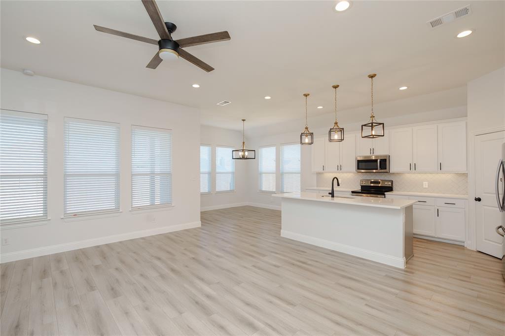 520 Mustang Lane Pilot Point, TX 76258 - Photo 3 of 15 a large white kitchen with kitchen island a refrigerator a sink dishwasher with a dining table and chairs