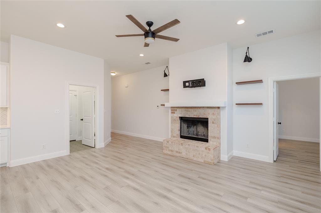 520 Mustang Lane Pilot Point, TX 76258 - Photo 4 of 15 an empty room with a fireplace and wooden floor