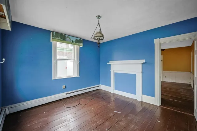a view of empty room with wooden floor and fireplace