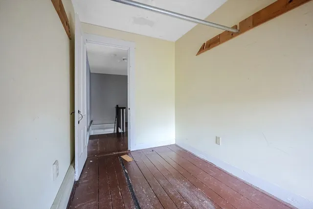 a view of a hallway with wooden floor and a bathroom