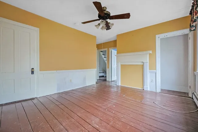 a view of an empty room with a window and wooden floor