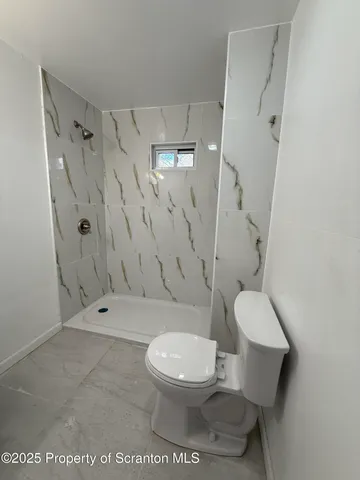 a white toilet sitting next to a bathroom sink and a shower