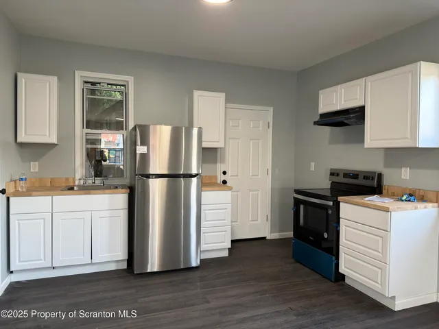 a kitchen with stainless steel appliances granite countertop a refrigerator stove a sink and a granite counter tops with wooden floors