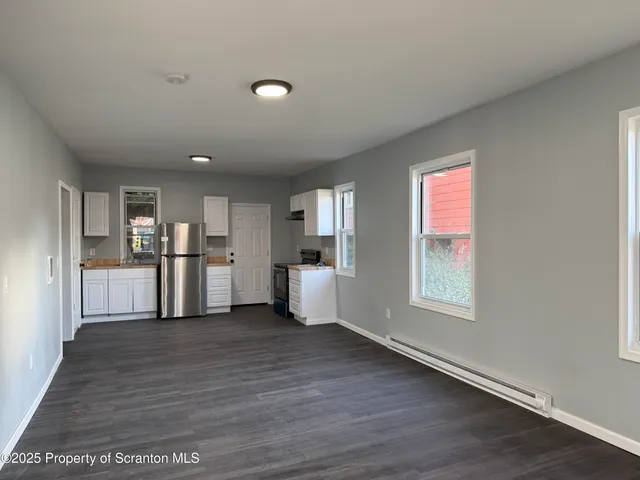 a view of a kitchen with wooden floor and windows