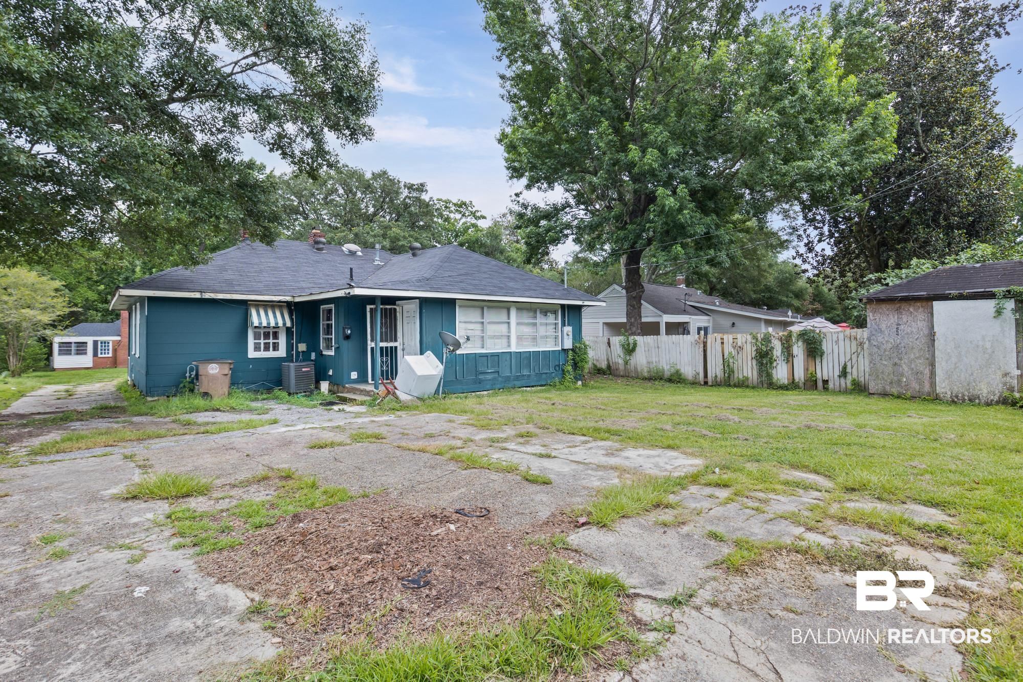 160 Glenn Avenue Mobile, AL 36606 - Photo 14 of 15 Property exterior featuring a teal facade with white trim, a dark shingle roof, and a striped window awning