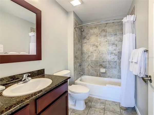 a bathroom with a granite countertop sink toilet mirror and bathtub