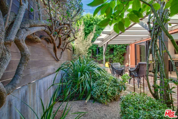 a backyard of a house with table and chairs under an umbrella