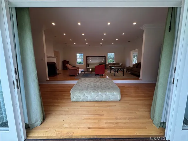 a living room with stainless steel appliances furniture wooden floor and a view of kitchen