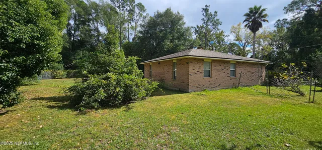 a backyard of a house with plants and large trees