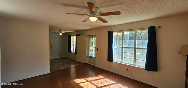 a view of an empty room with window and wooden floor