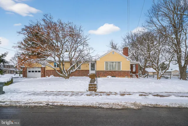 a front view of a house with a yard covered in snow