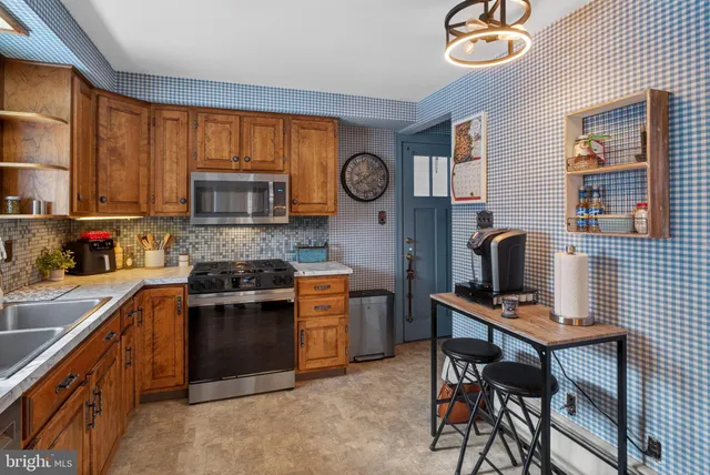 a kitchen with stainless steel appliances a stove top oven a sink a dining table and chairs