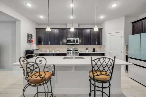 a kitchen with stainless steel appliances granite countertop a stove a sink a microwave a refrigerator and chairs