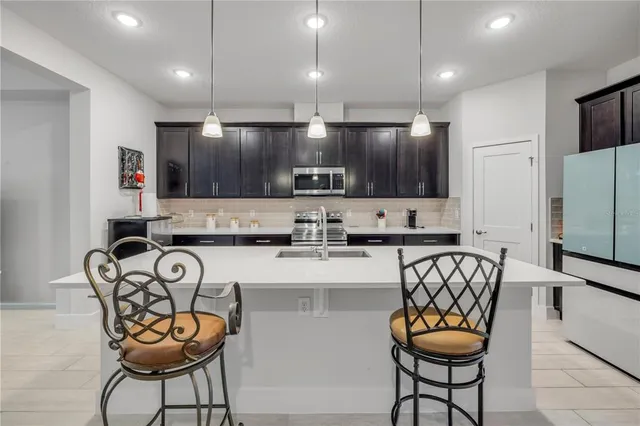 a kitchen with stainless steel appliances granite countertop a stove a sink a microwave a refrigerator and chairs