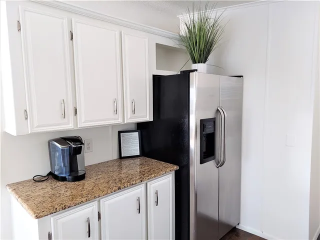 a kitchen with stainless steel appliances granite countertop a refrigerator a sink and white cabinets