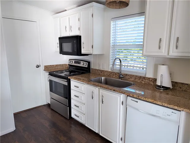 a kitchen with granite countertop a sink and a stove top oven
