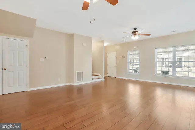 a view of an empty room with a window and wooden floor