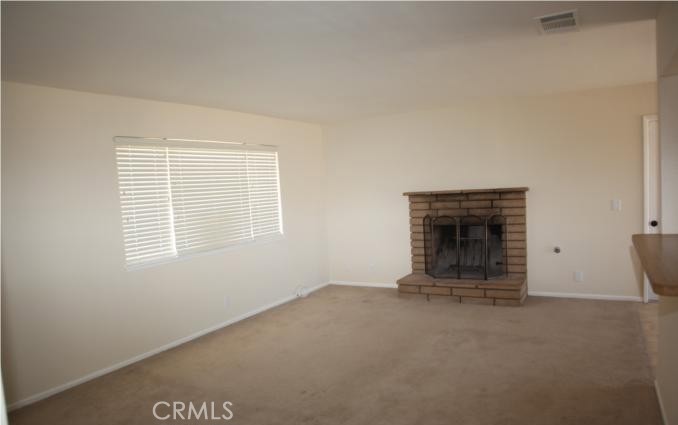 21110 Sandia Road Apple Valley, CA 92308 - Photo 2 of 3 an empty room with a fireplace and window