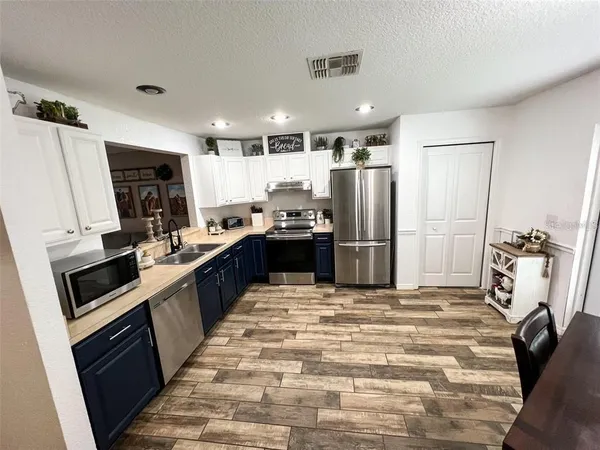 a kitchen with stainless steel appliances wooden floor dining table chairs and a refrigerator