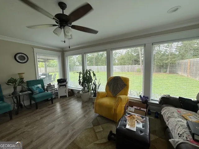 a living room with furniture ceiling fan and a large window