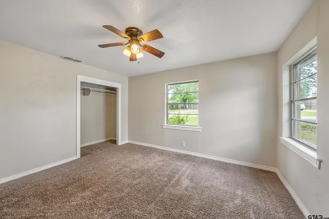 an empty room with windows and chandelier fan