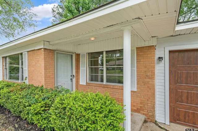 a front view of a house with a large window and potted plants