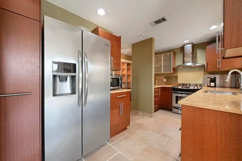 a kitchen with stainless steel appliances granite countertop a refrigerator a sink a stove and a refrigerator