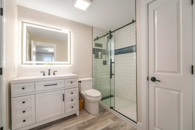 a bathroom with a double vanity sink toilet mirror and window