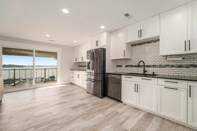 a kitchen with stainless steel appliances granite countertop a refrigerator sink and wooden cabinets