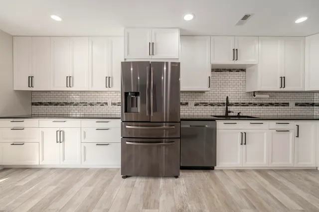 a kitchen with kitchen island granite countertop a sink cabinets and stainless steel appliances