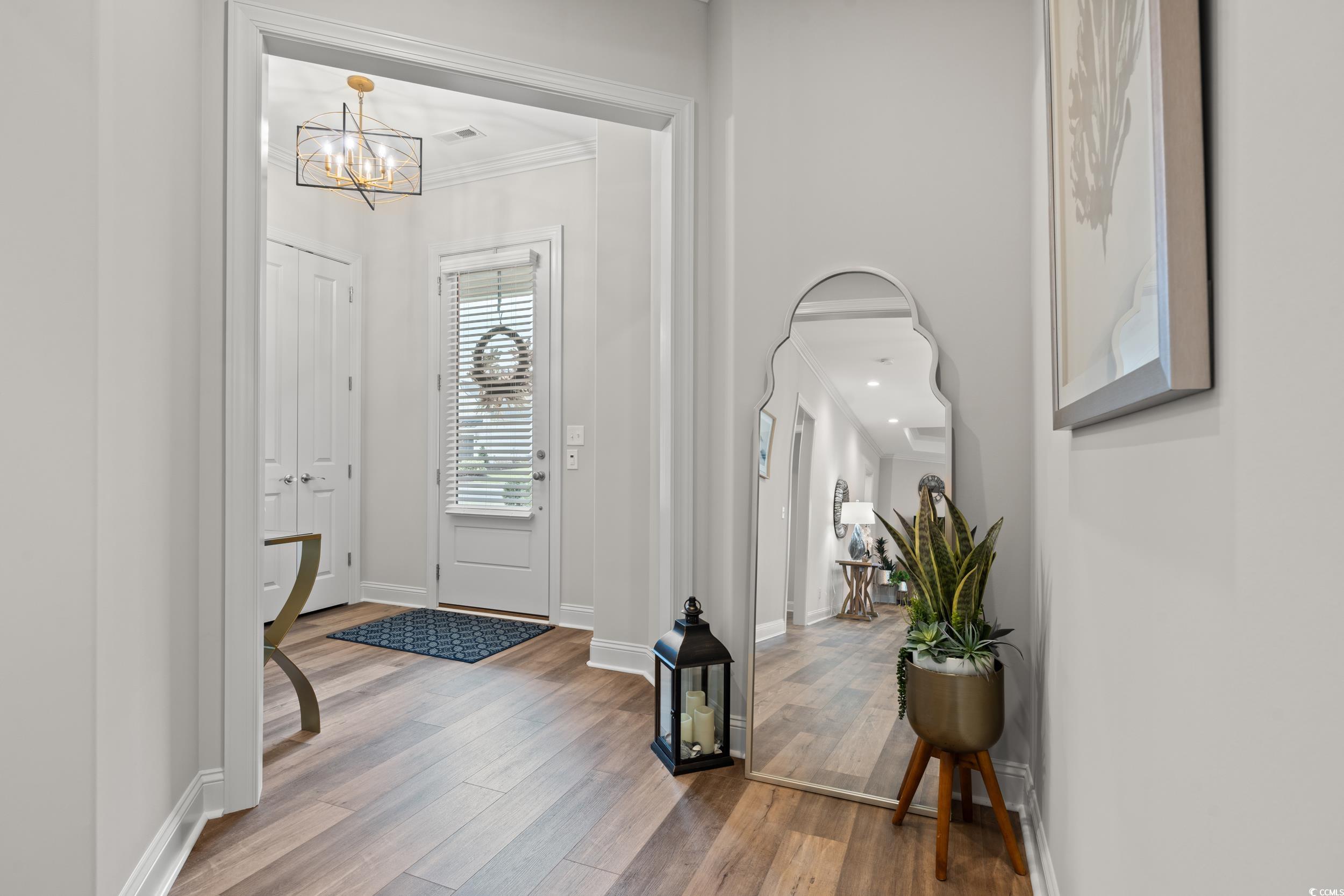 8338 Cape Dutch Loop Myrtle Beach, SC 29572 - Photo 5 of 39 Foyer entrance featuring wood finished floors, ornamental molding, arched walkways, and a chandelier