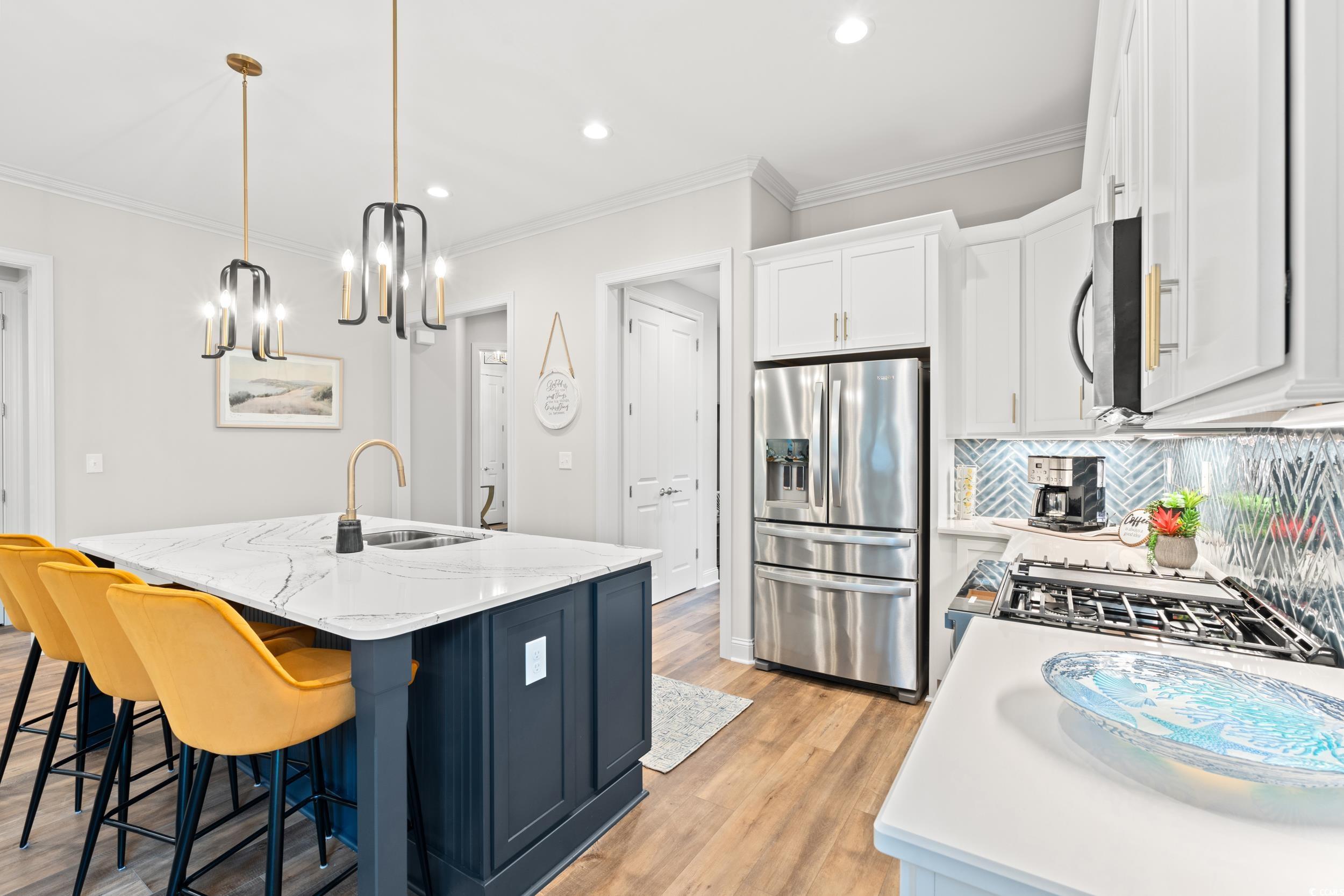 8338 Cape Dutch Loop Myrtle Beach, SC 29572 - Photo 7 of 39 Kitchen featuring decorative light fixtures, appliances with stainless steel finishes, white cabinets, light stone counters, and a kitchen island with sink