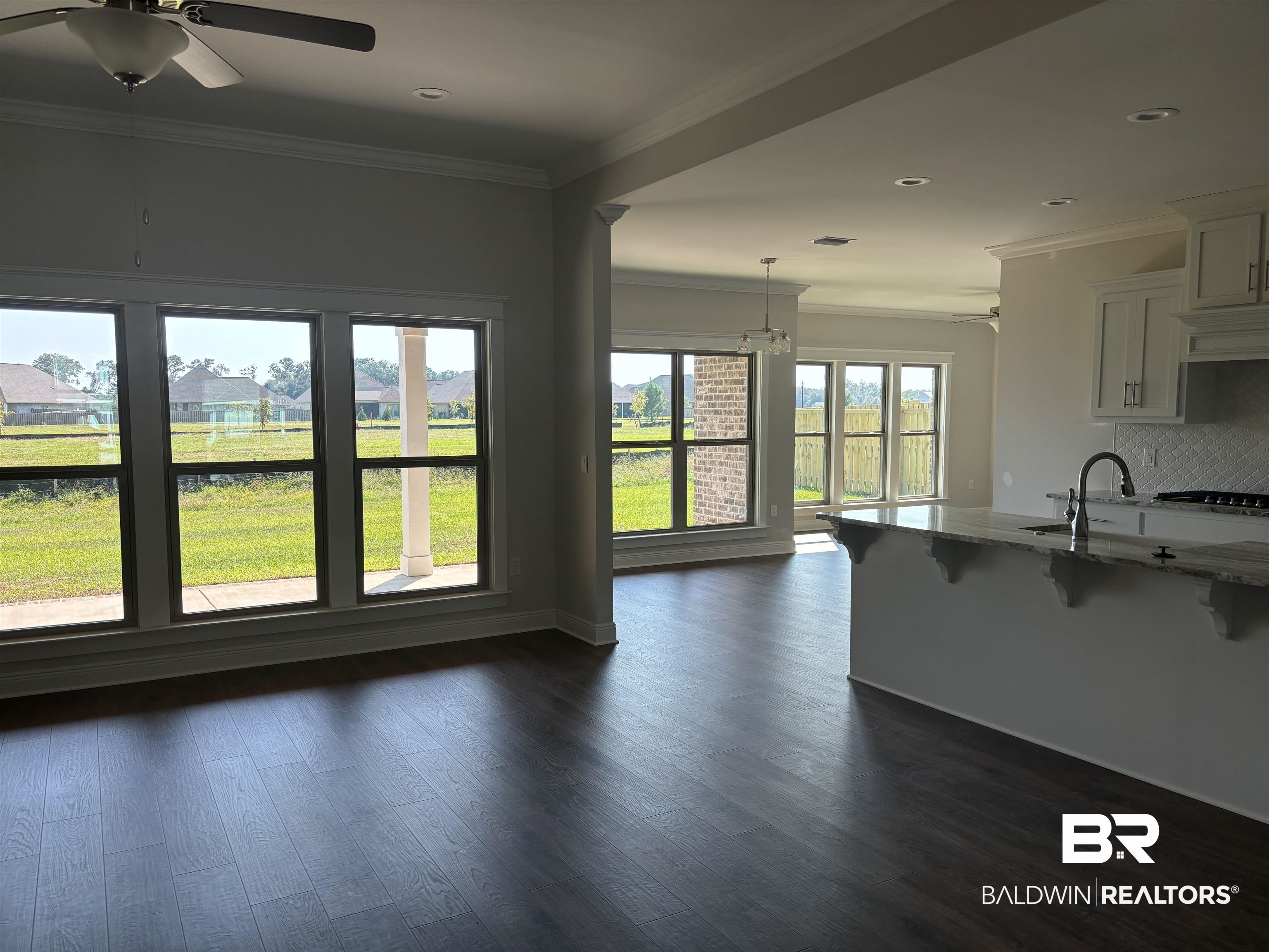 388 Garrison Boulevard Fairhope, AL 36532 - Photo 8 of 34 Kitchen with tasteful backsplash, decorative light fixtures, light stone counters, dark hardwood / wood-style floors, and ornamental molding