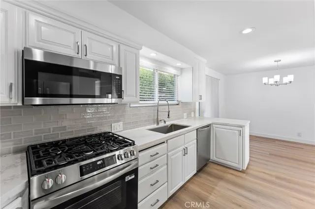 a kitchen with stainless steel appliances white cabinets granite counter tops and a window